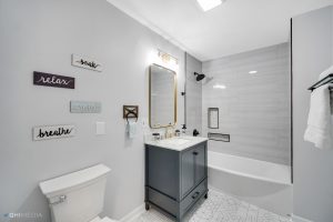 After A bathroom with a toilet, sink, and mirror featuring an East Chicago siding